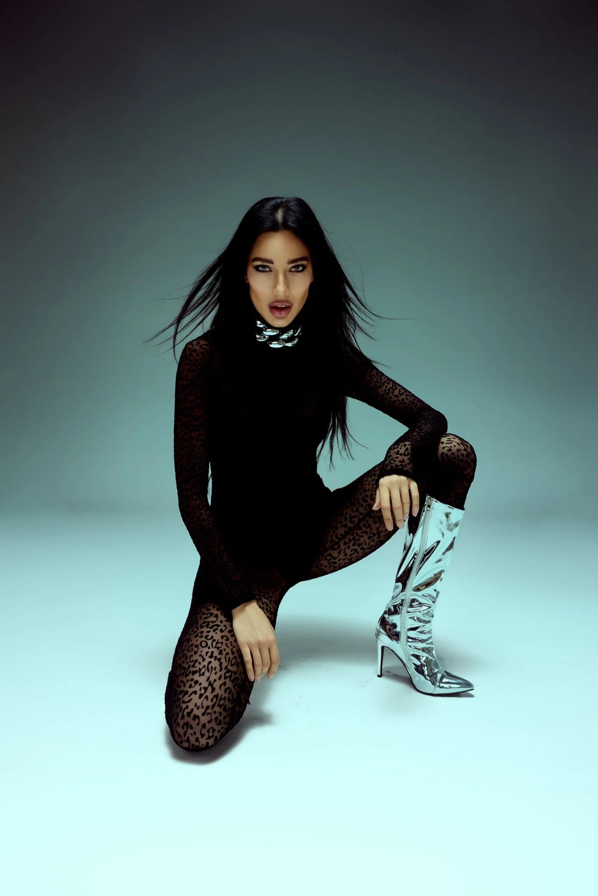 Black bodysuit with silver boots on a mint backdrop