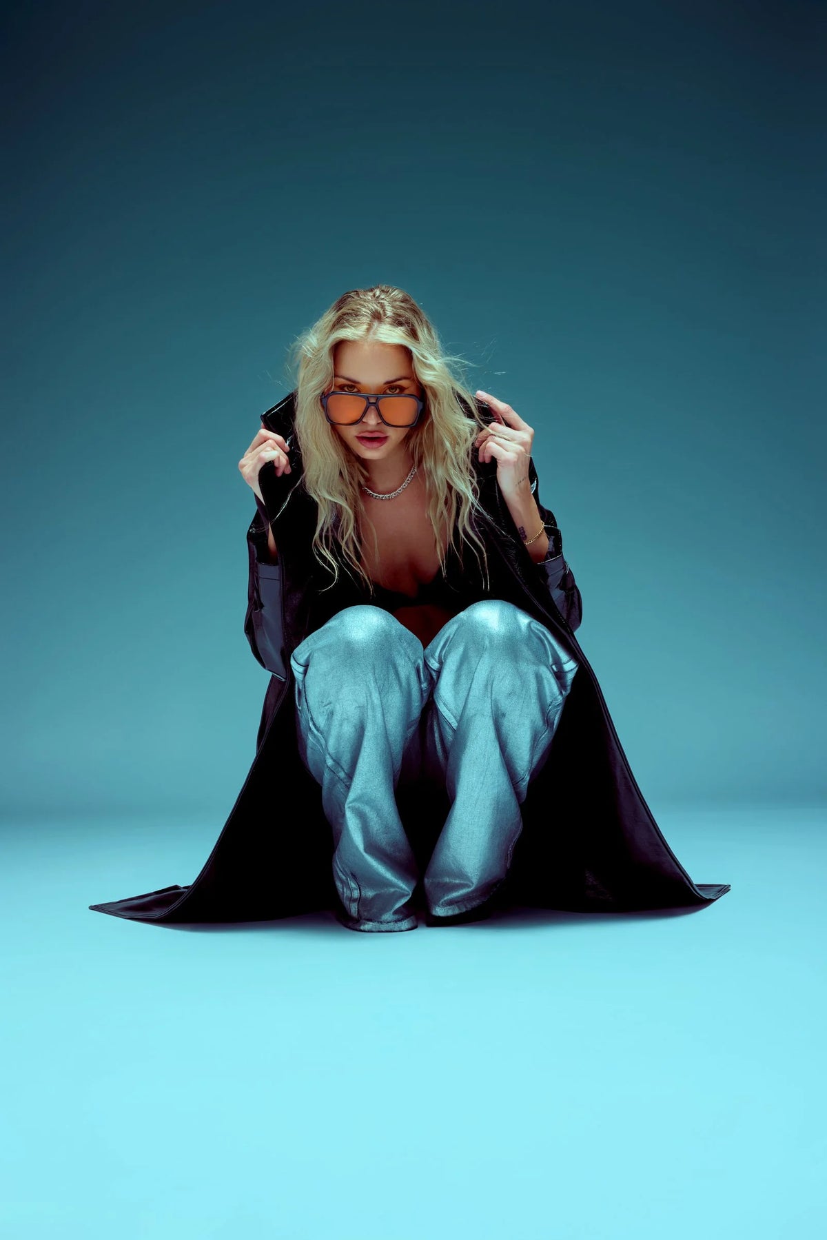 Black coat and denim, seated pose with glasses