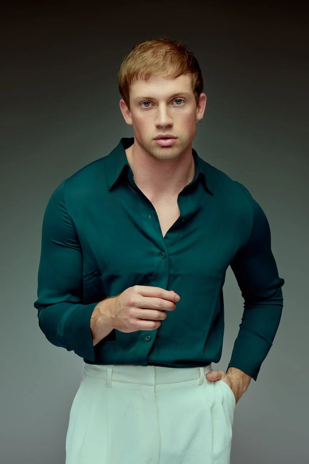 Man in a green shirt, relaxed studio portrait on a blue backdrop
