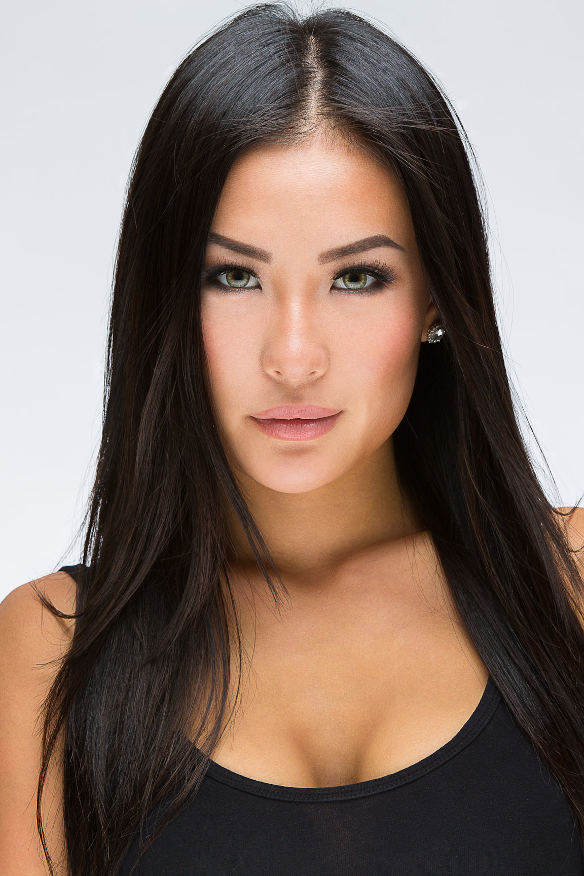 Studio headshot of a woman with long dark hair in a black top on a light grey backdrop