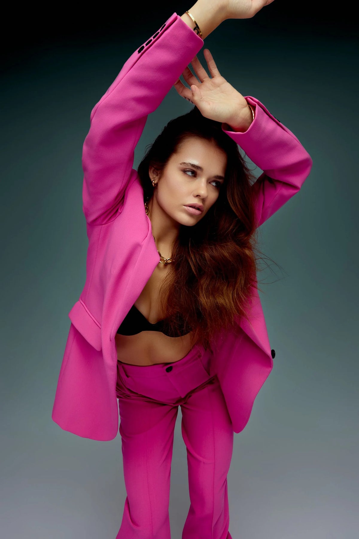 Pink suit, arms raised, on a teal backdrop