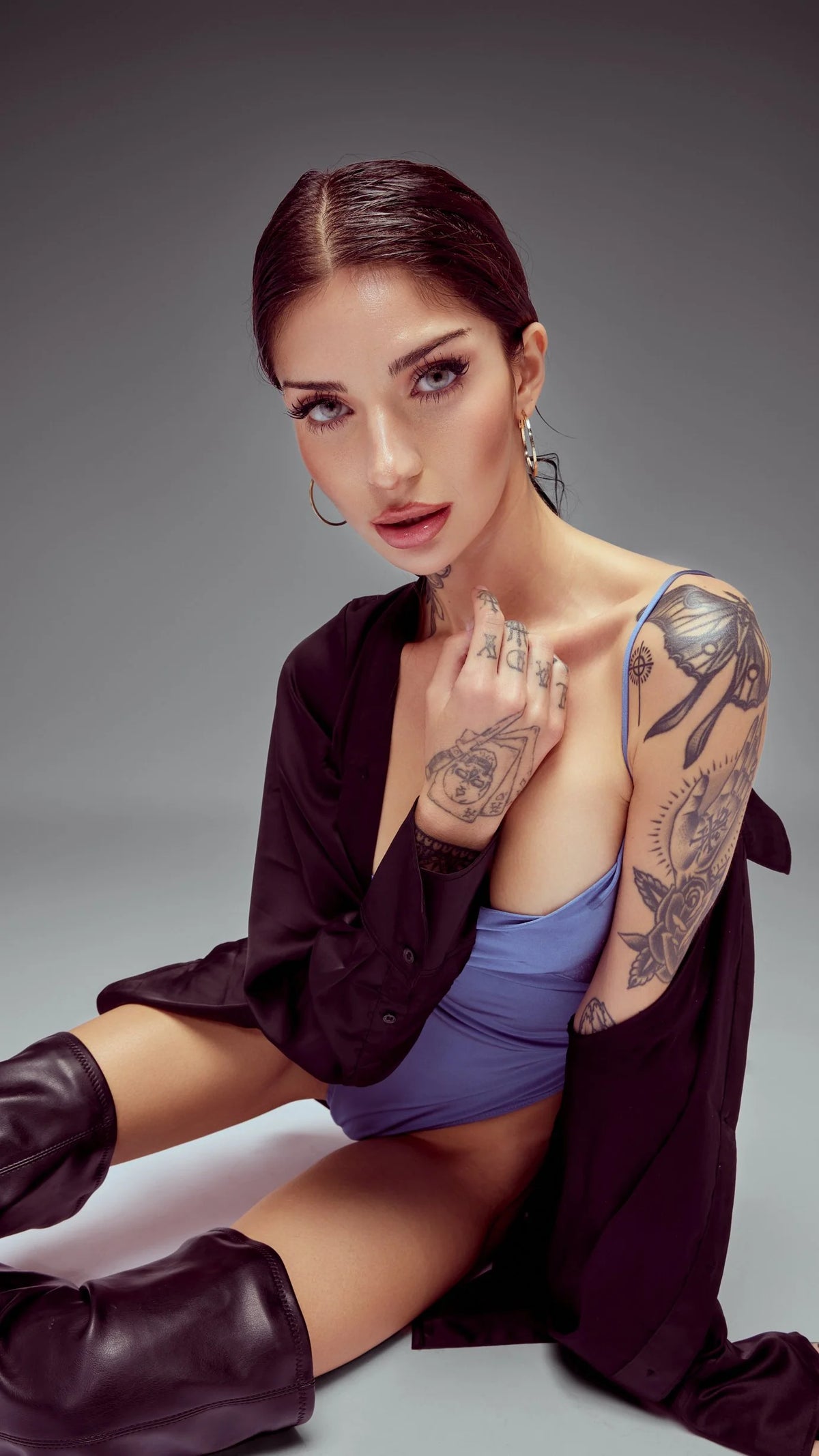 Tattooed model in a lavender bodysuit and burgundy jacket