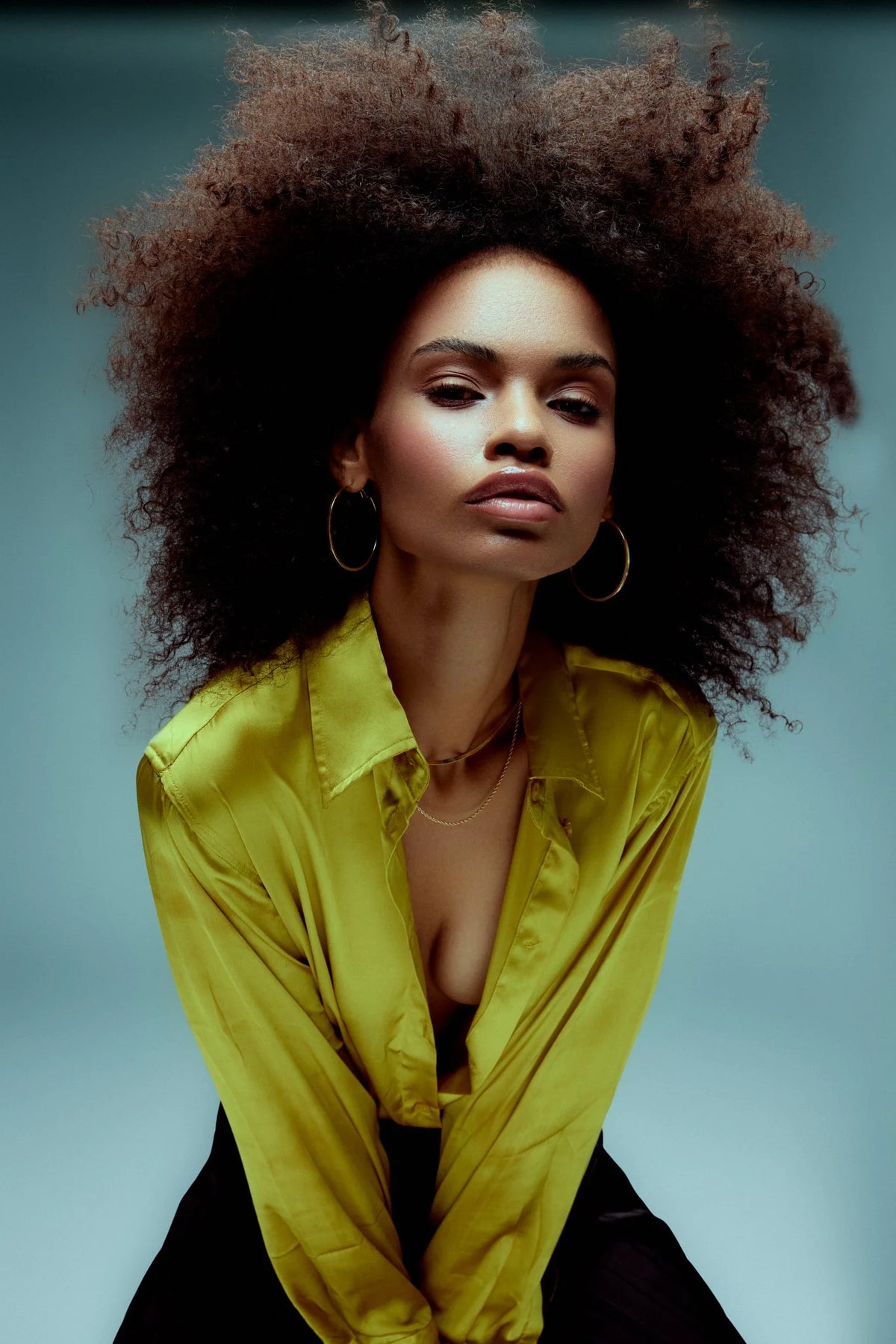 Woman with natural curls in a chartreuse satin blouse