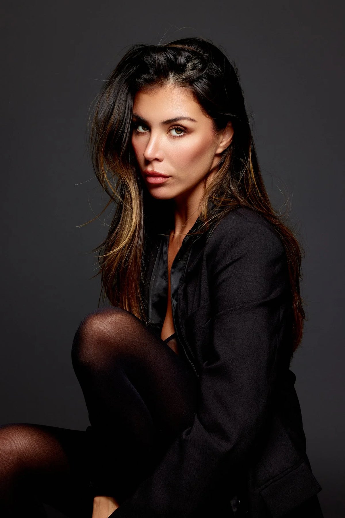 Woman with long dark hair in black, low-key studio portrait