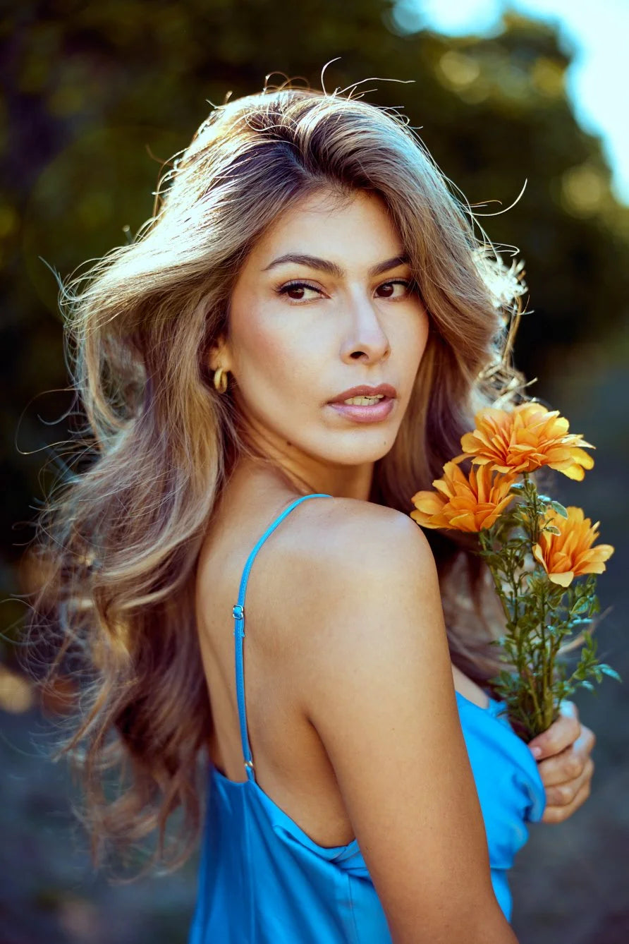 Woman in a blue slip dress holding orange flowers