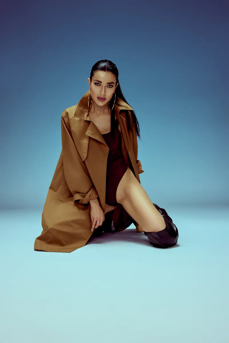 Model in a camel trench on a blue set